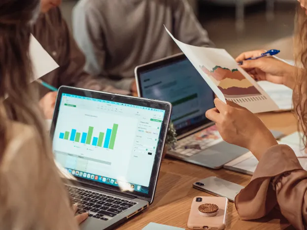 Business people working together analysing charts on laptops and papers