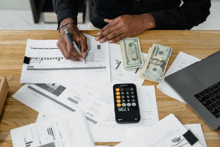 An accountant's workspace with calculator, money, and laptop on a desk