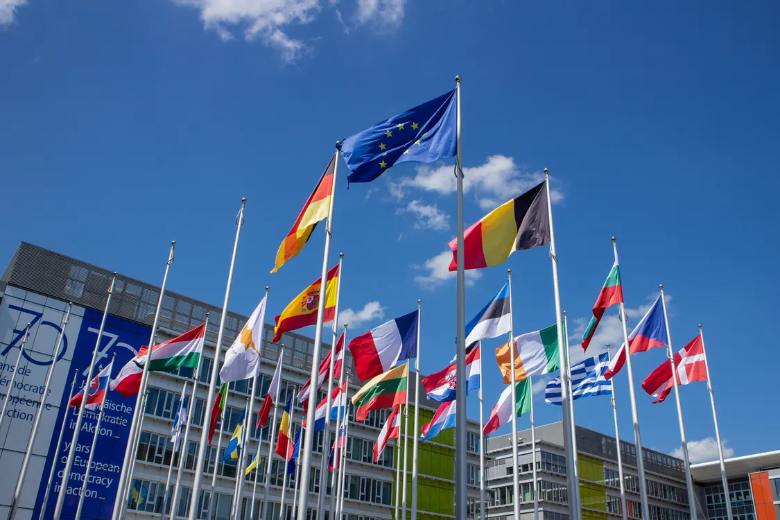 Low angle view of European Union flags on flagpoles against a blue sky
