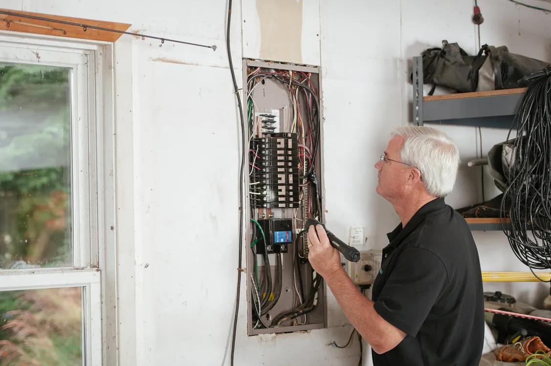 Electrician inspecting a residential fuse box during an EICR inspection
